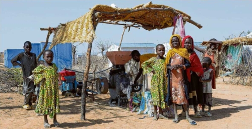 African children standing in front of a motor-driven mill