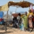 African children standing in front of a motor-driven mill