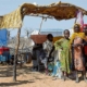 African children standing in front of a motor-driven mill